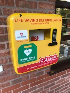 a yellow defibrillator box fixed onto a wall